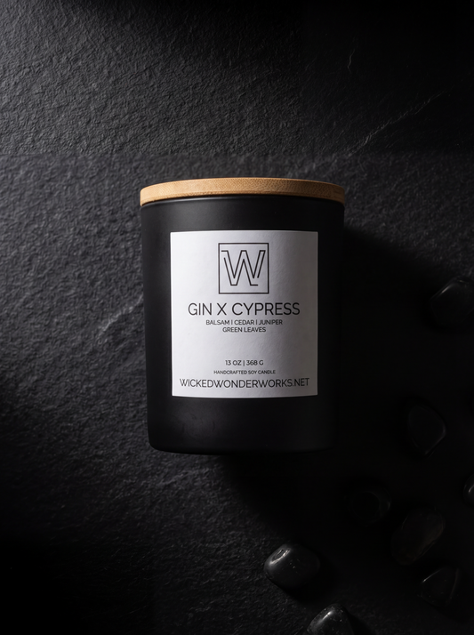 Candle labeled 'Gin X Cypress' with a wooden lid on a dark textured background